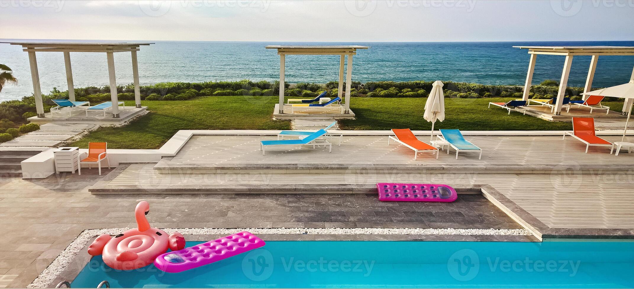 Inflatable float rubber objects in the form of a pink mattress and flamingo in the blue water of the pool in sunset photo