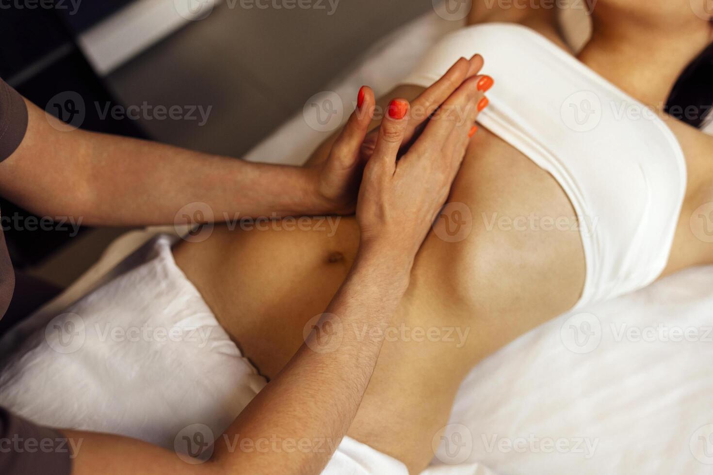 Close up of young woman getting belly massage in spa salon photo