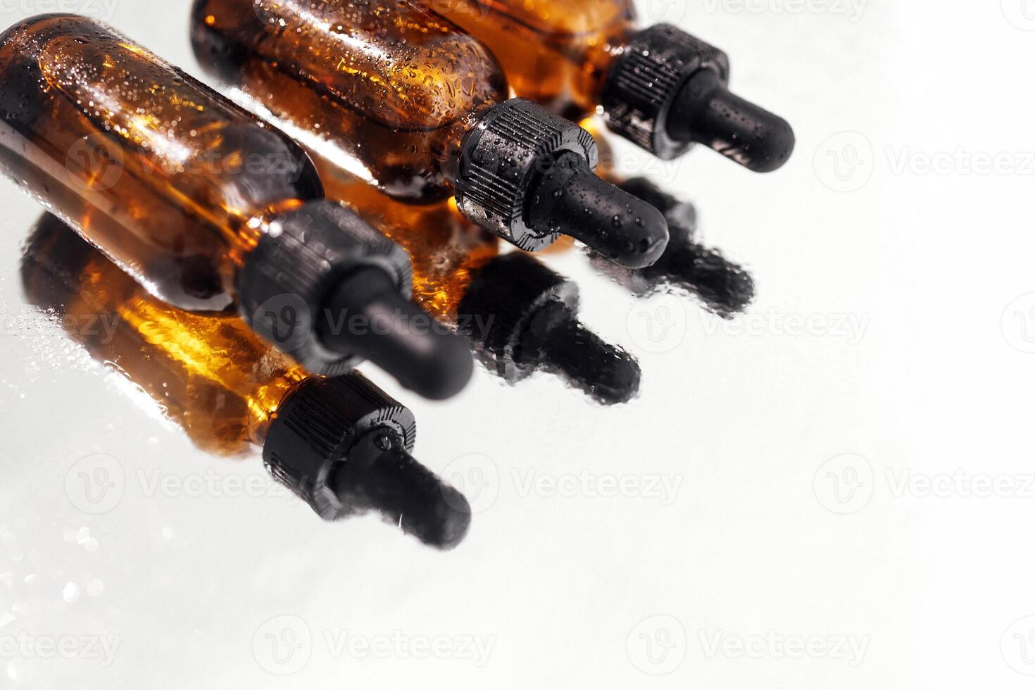 Brown serum or oil glass mock up three bottles with pipette on white background. Group of bottles with drops on them and their reflection on a mirror surface. photo
