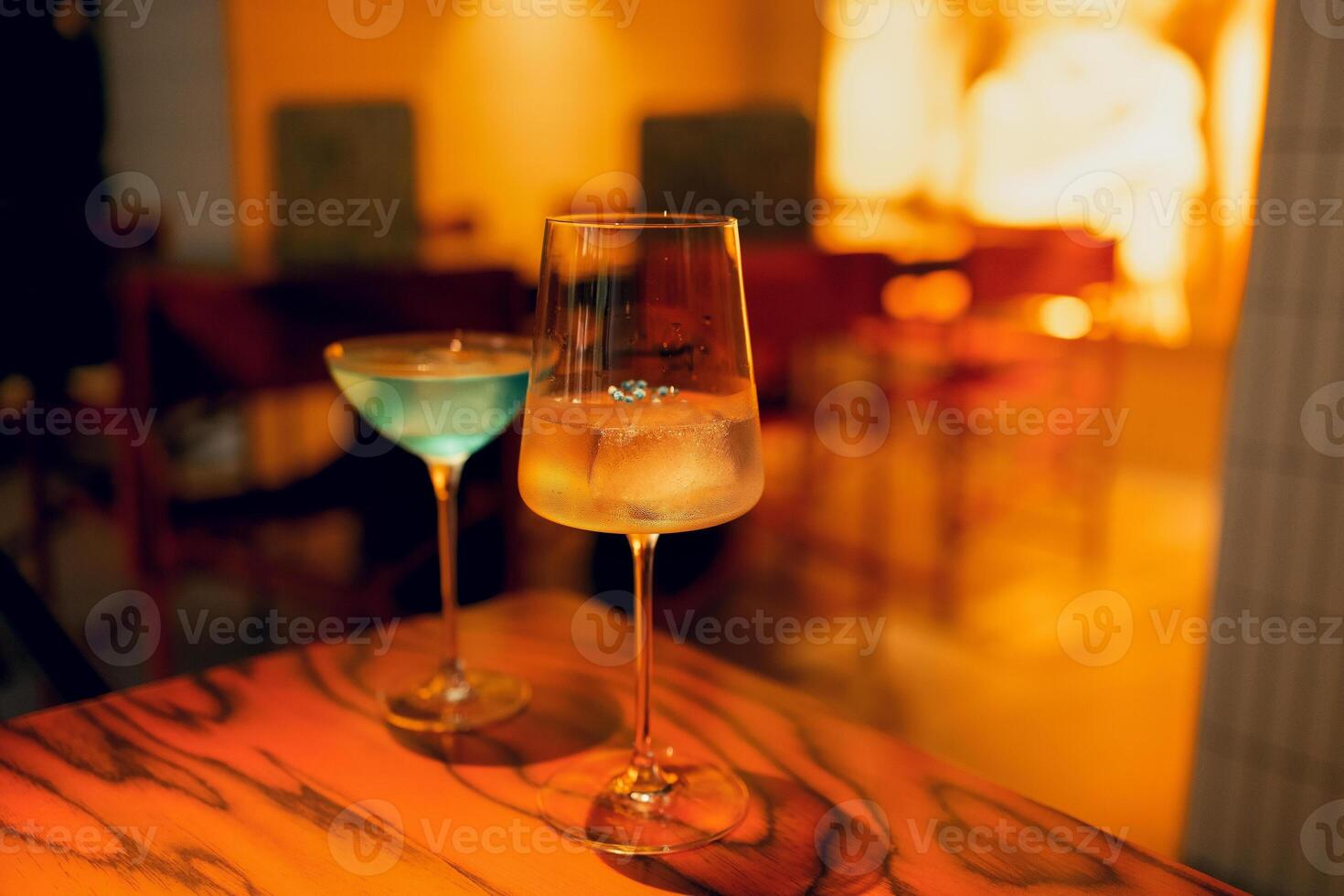 Two delicious ice cold cocktails in exquisite glasses stand on a wooden table in a restaurant. photo