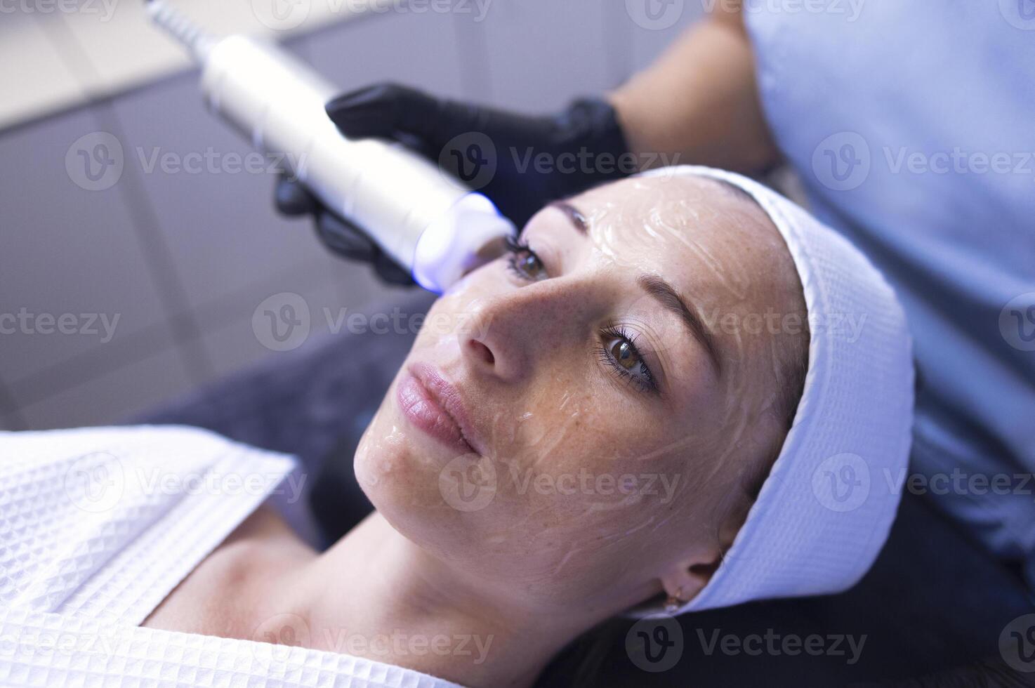 Closeup of face of beautiful relaxing girl undergoing hardware cosmetology procedure in spa photo