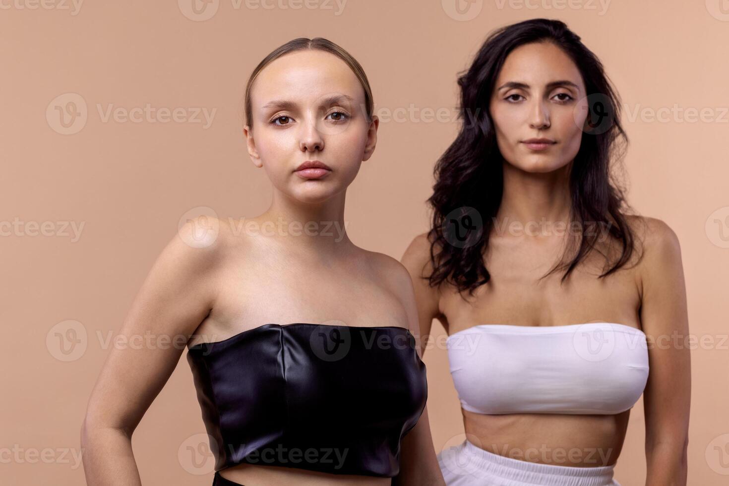 women wearing tops while posing together on beige background photo