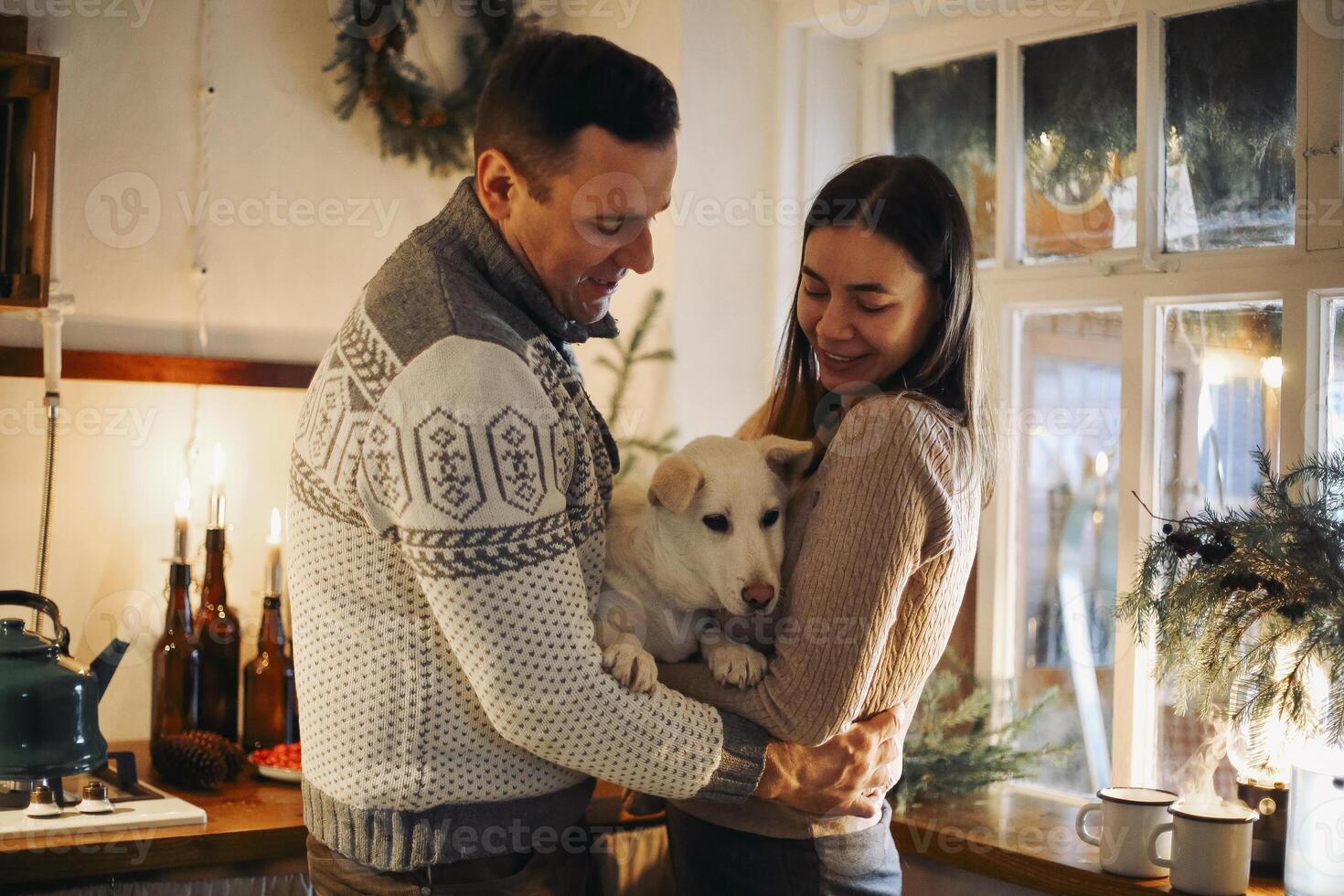 Young happy couple in love with cute little dog enjoying winter holiday season in cozy warm house photo