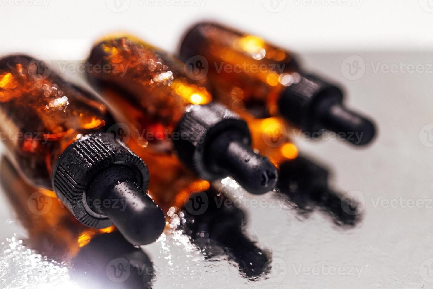 Group of bottles with drops on them and their reflection on a mirror surface photo