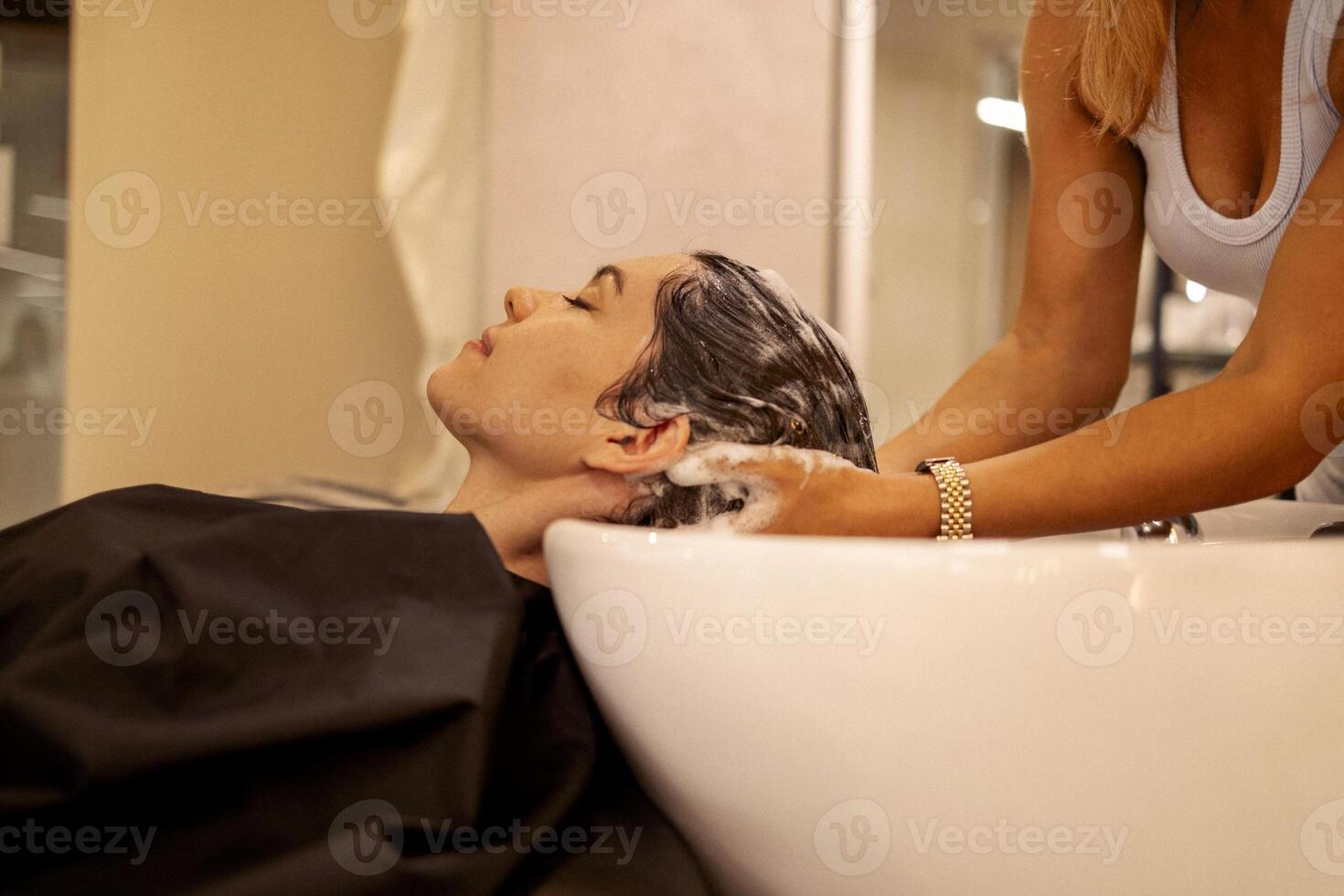 Cheerful young brunette womn enjoying head massage and washing hair photo