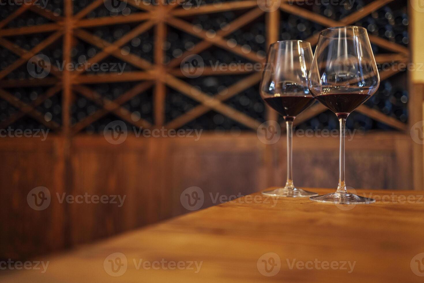Wine bottles on a wooden shelf. Wine bar. Two glasses with red wine on wooden background photo