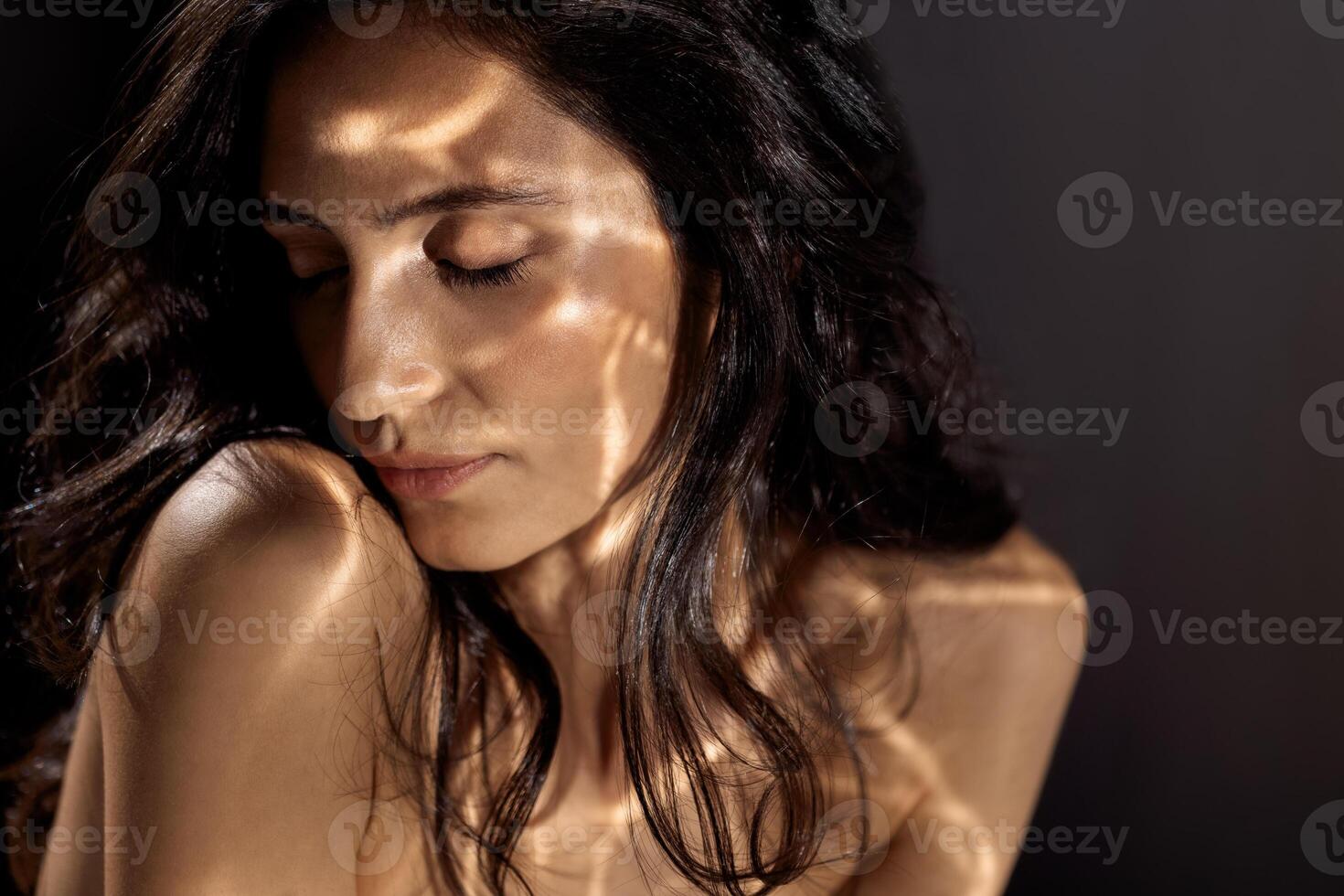 Studio fashion portrait of a charming young woman sitting with her eyes closed photo