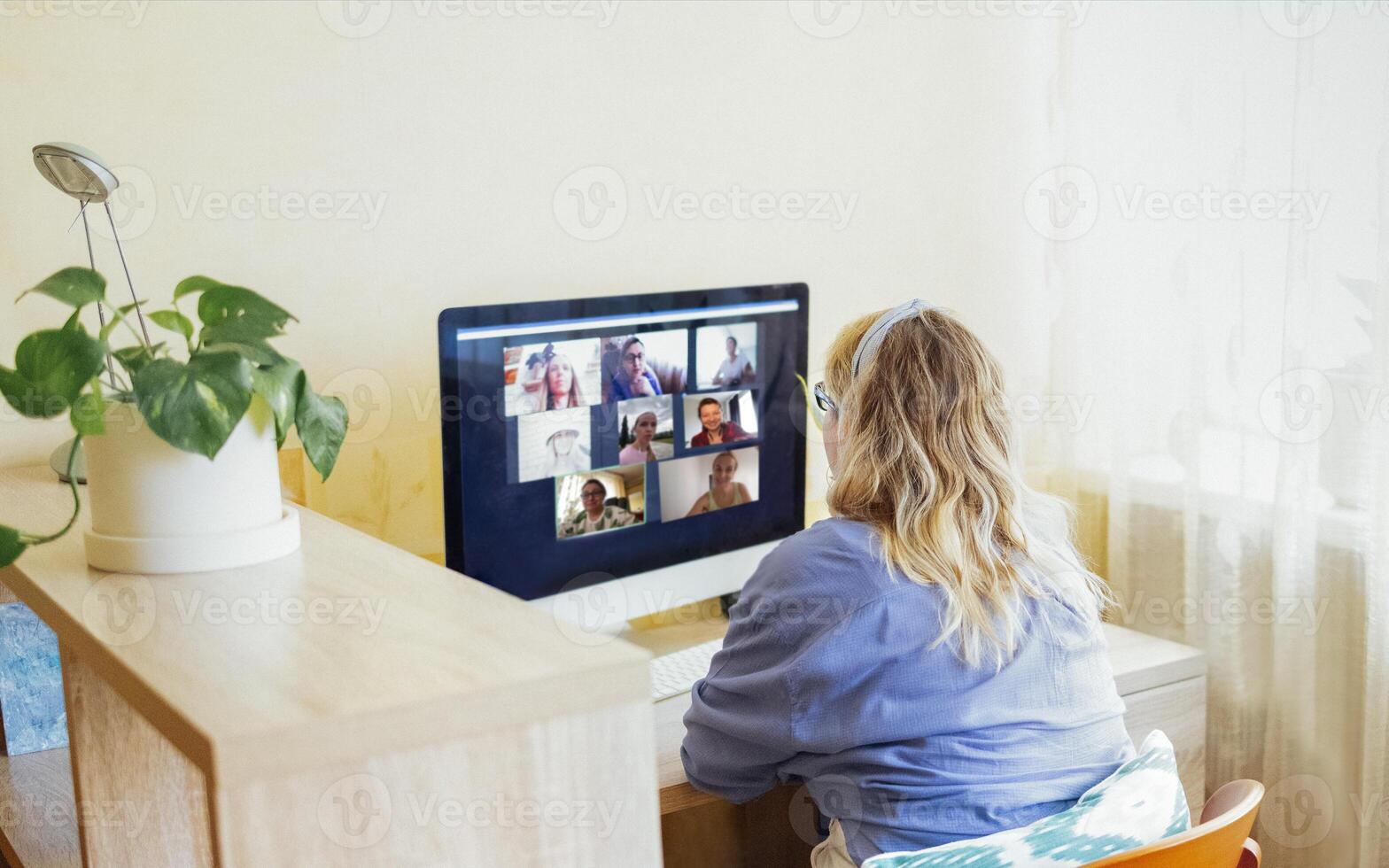 Young woman sits in front of computer monitor and talks via link. photo