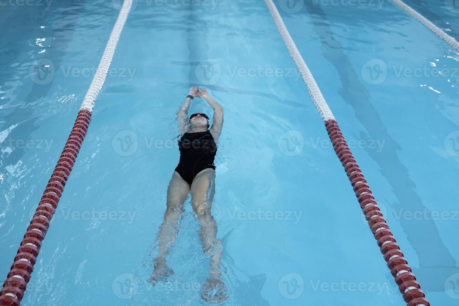 Young swimmer wears a swim cap and puts away goggles photo