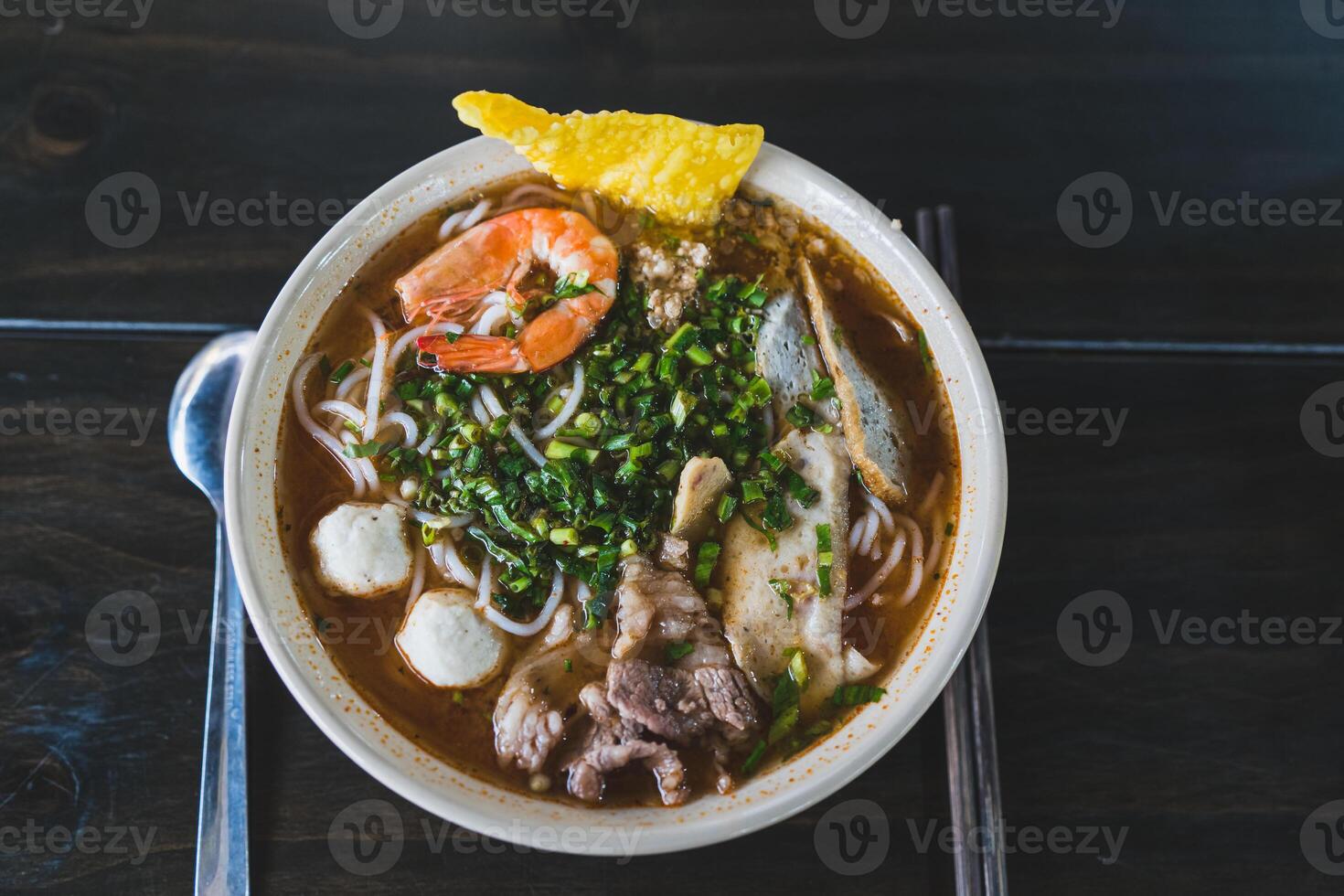 Tom Yum soup - Thai soup with prawns and rice noodles on wooden table in Vietnam photo