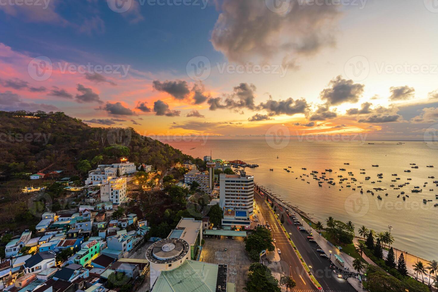 Top view with beautiful sunset and boats. Panoramic view of Vung Tau coast from above with waves, beach, streets, coconut trees and Tao Phung mountain in Vietnam photo