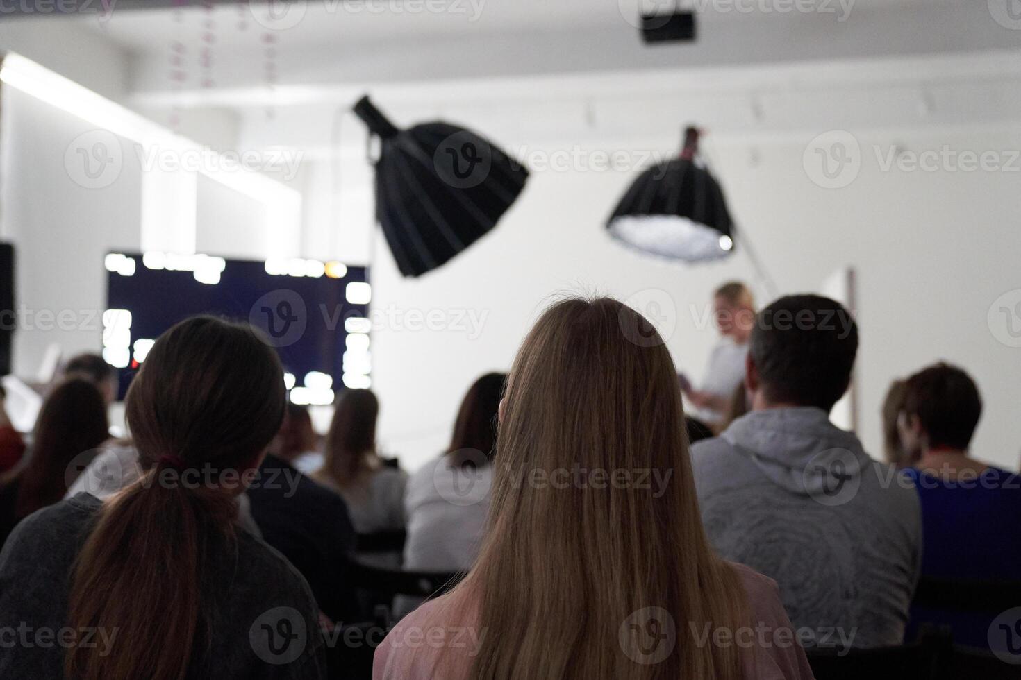 Unrecognizable people in the audience, rear view. Sitting at a lecture or meeting at the university. business and entrepreneurship or the concept of learning. photo