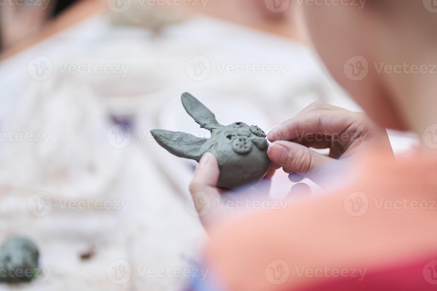 A master class for children on making toys from clay. A boy sculpts a figurine of an animal. Selective close-up focus with copy space photo