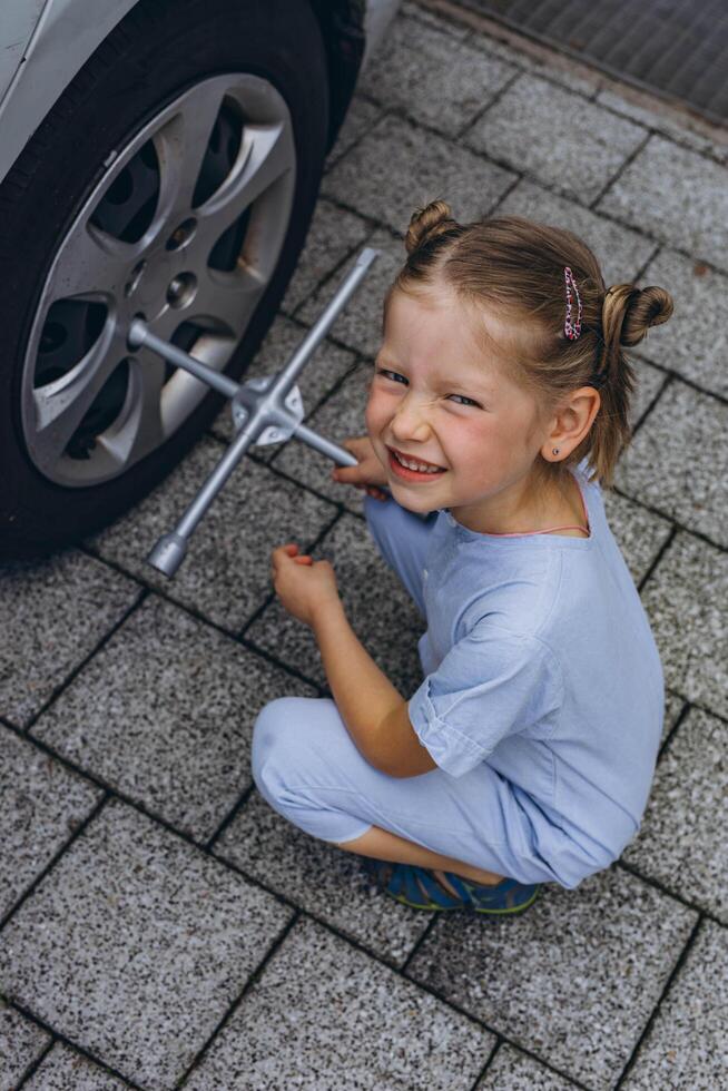 Cute little girl helps her father to change wheel,Kid helping to fix problems with car photo