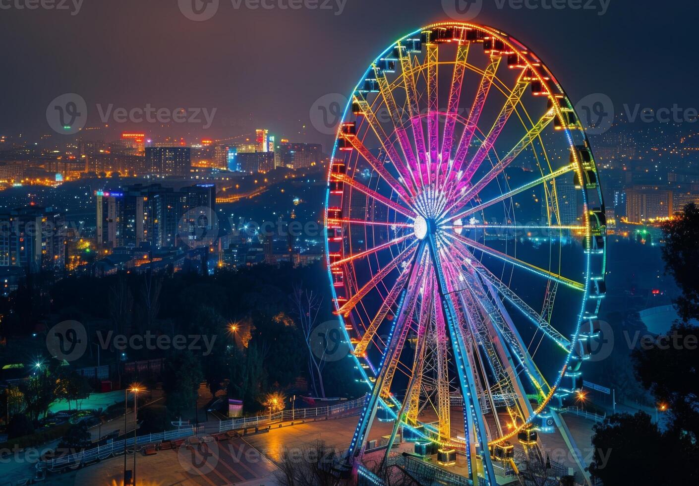 A colorful Ferris wheel illuminated at night with a cityscape in the background photo