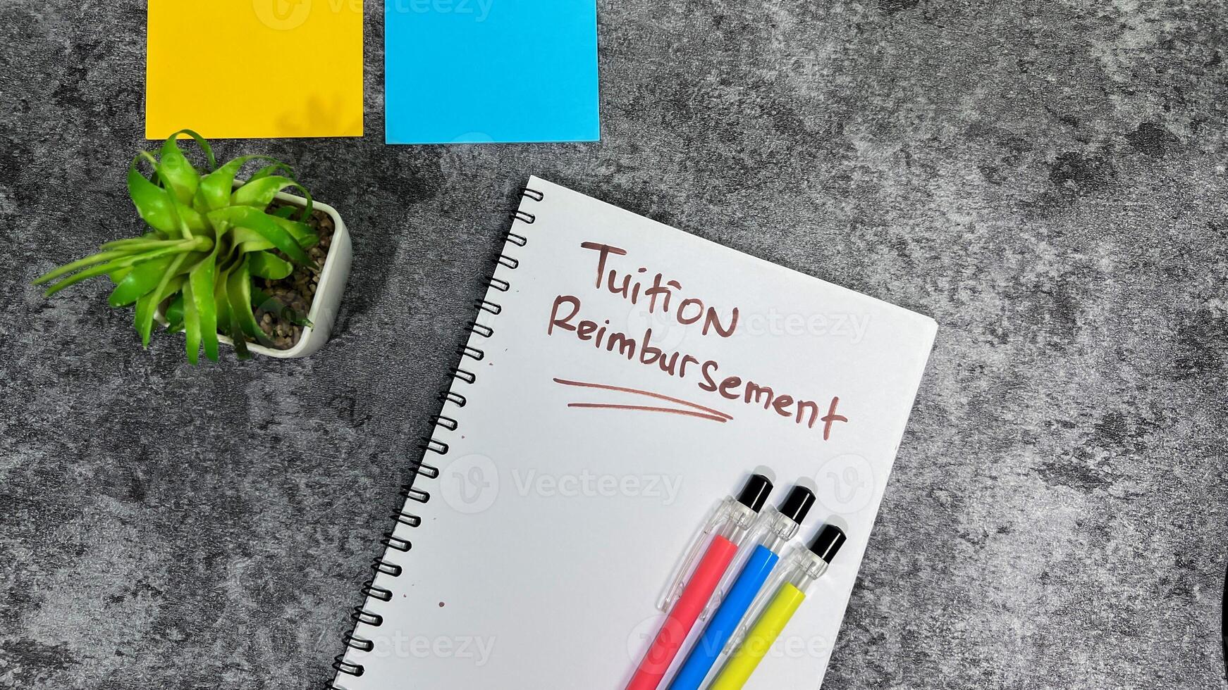 Concept of Tuition Reimbursement write on book isolated on Wooden Table. photo