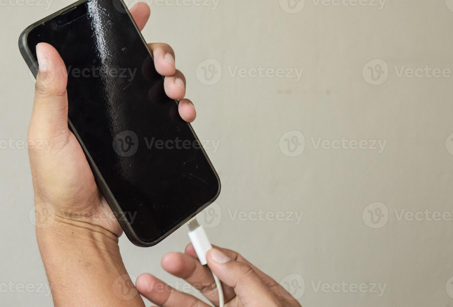 Mobile smart phones charging. Man hands plugging a charger in a smartphone photo