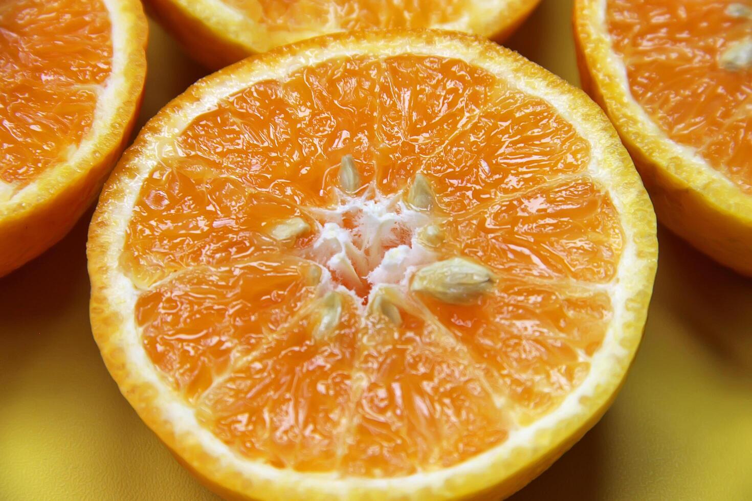 Sliced juicy orange fruit on yellow photo