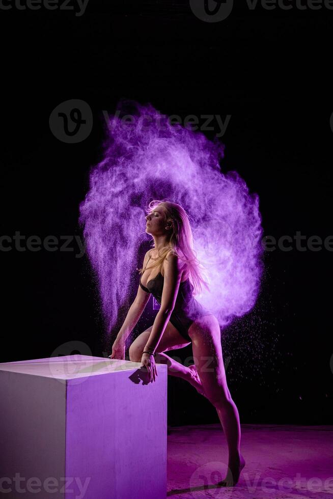 Young woman posing with purple particles in the air photo