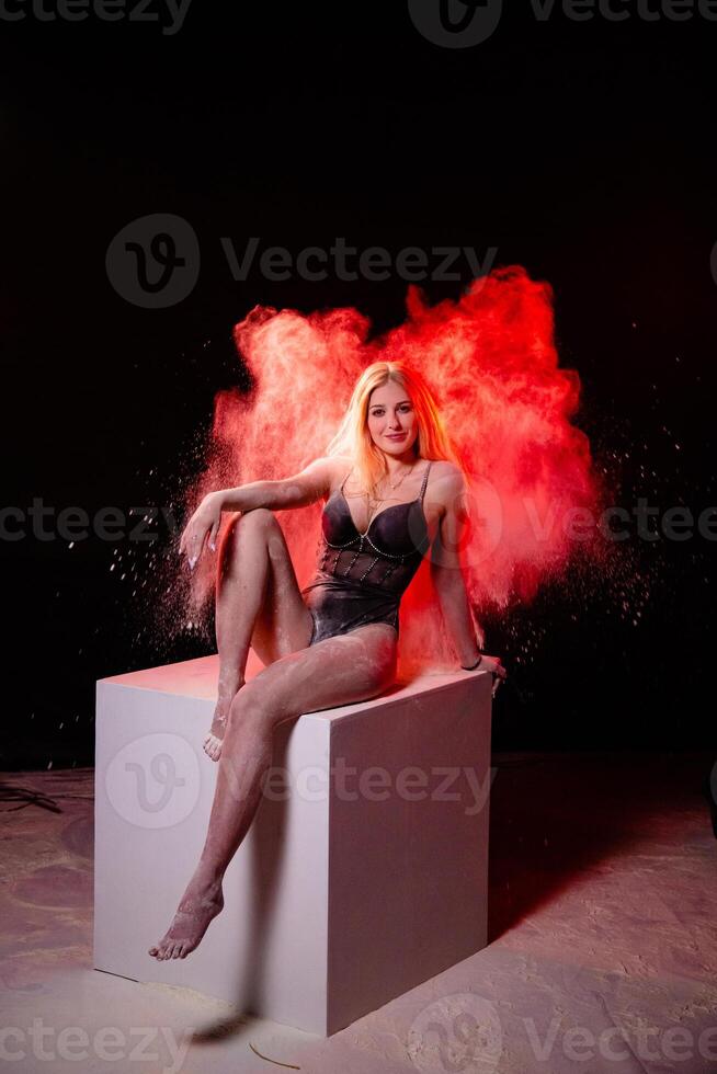 Young woman posing with red particles in the air photo
