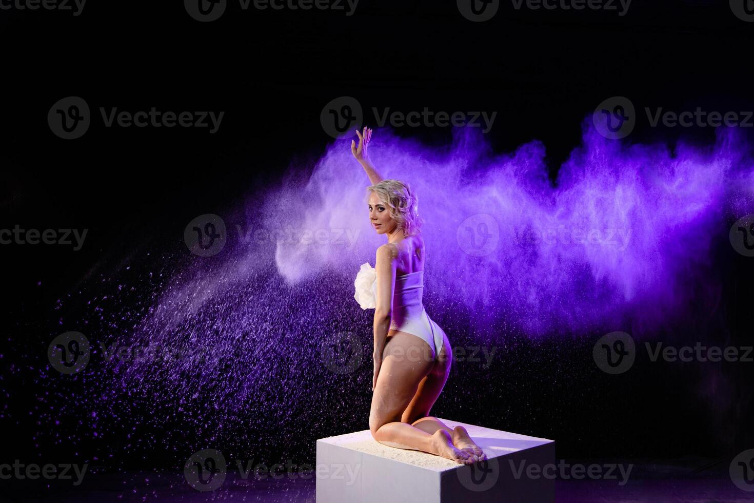 Woman posing with purple particles sprayed in air photo