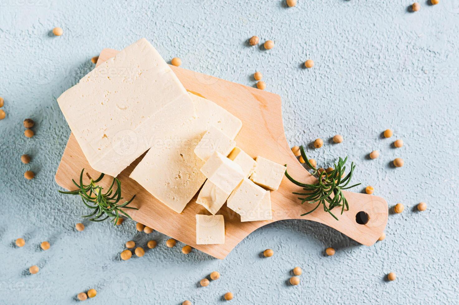 Close up of fresh sliced soy cheese tofu and rosemary on a wooden board on the table top view photo
