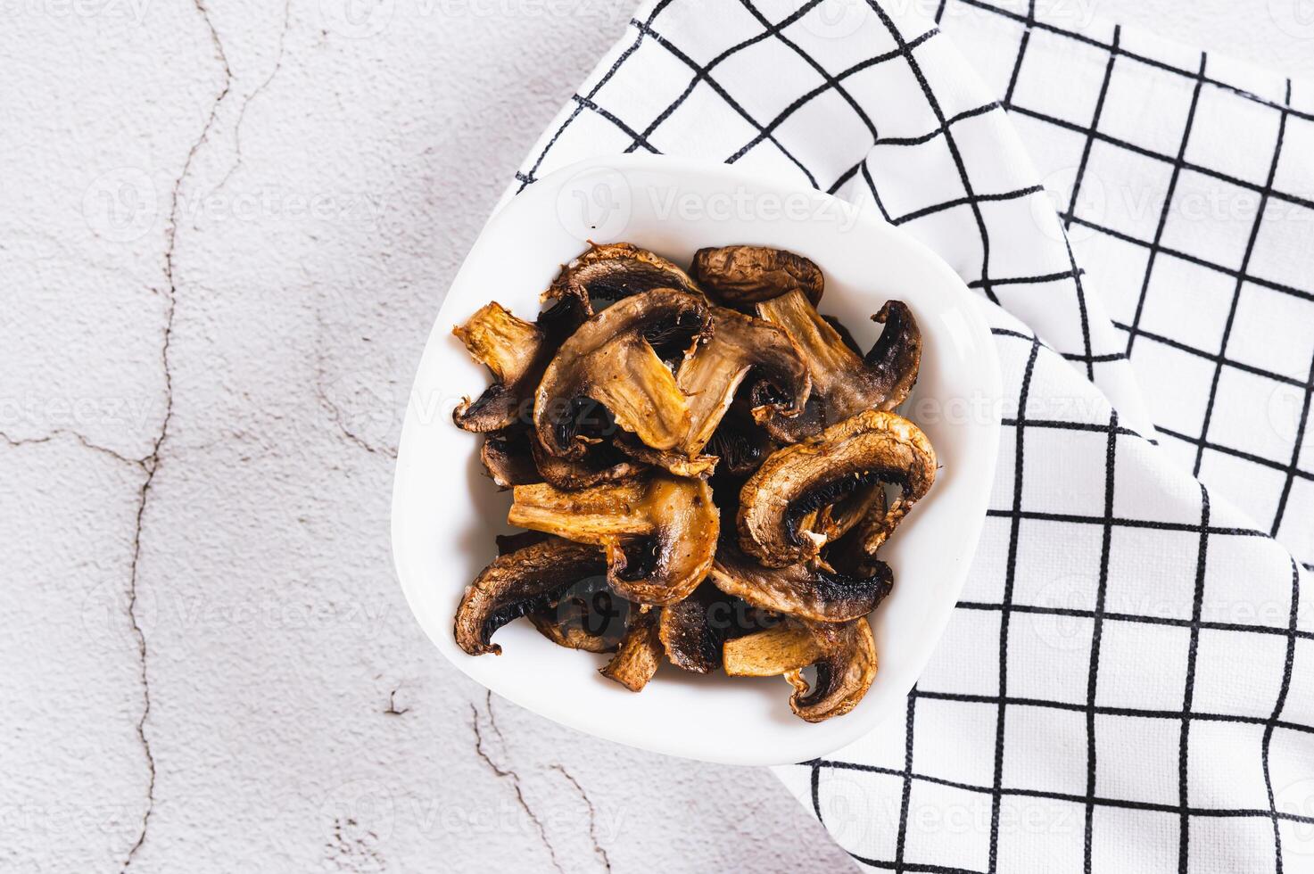 Close up of crispy mushroom chips for snack in bowl on table top view photo