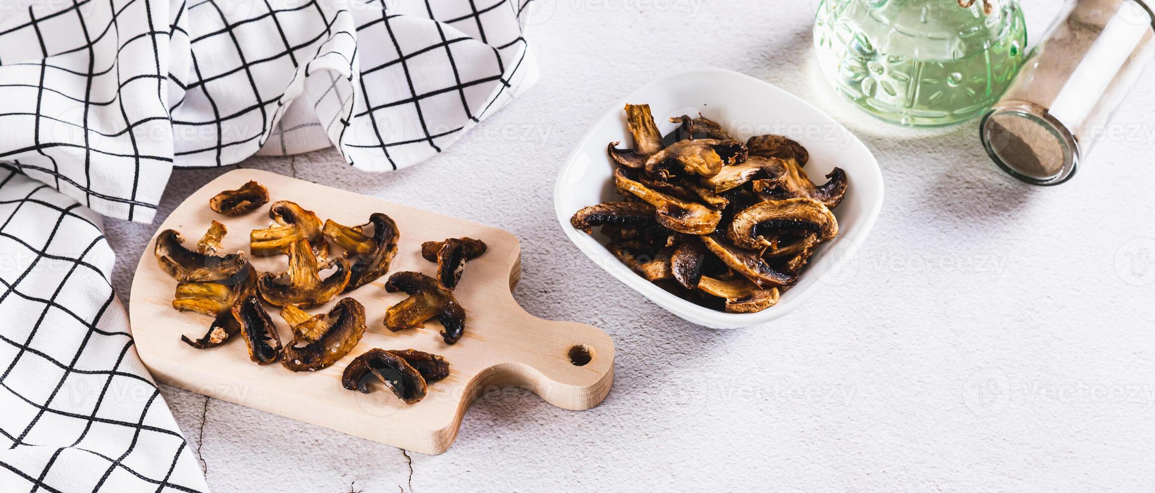 Crispy mushroom chips for snack in bowl and on a board on table web banner photo