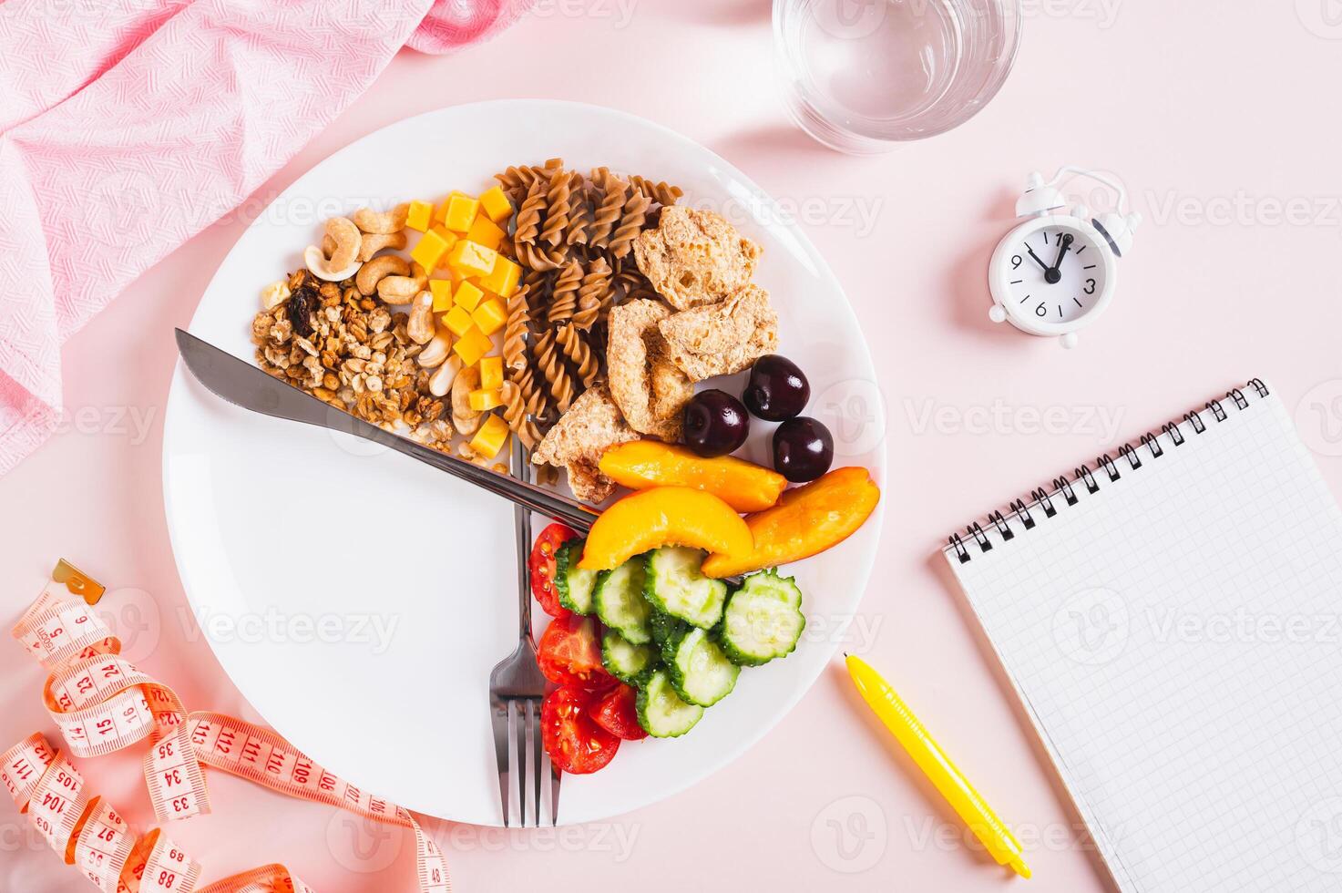 Concept individual meal plan by time food on plate, notebook and alarm clock on table top view photo