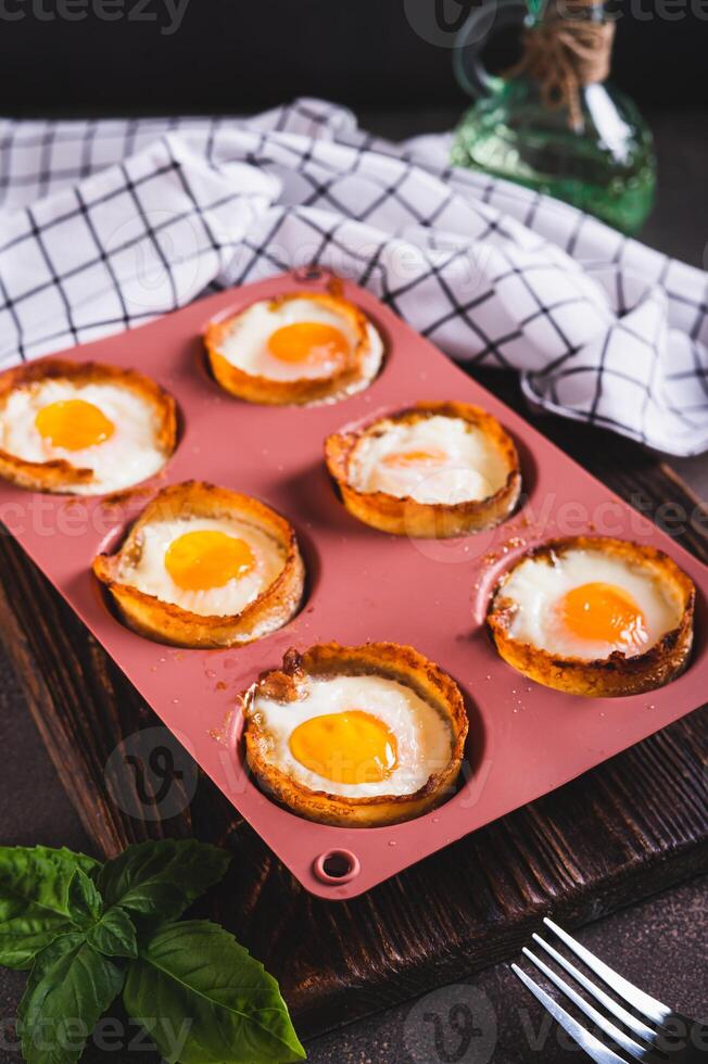 Chicken eggs baked in bacon in a baking dish on the table vertical view photo