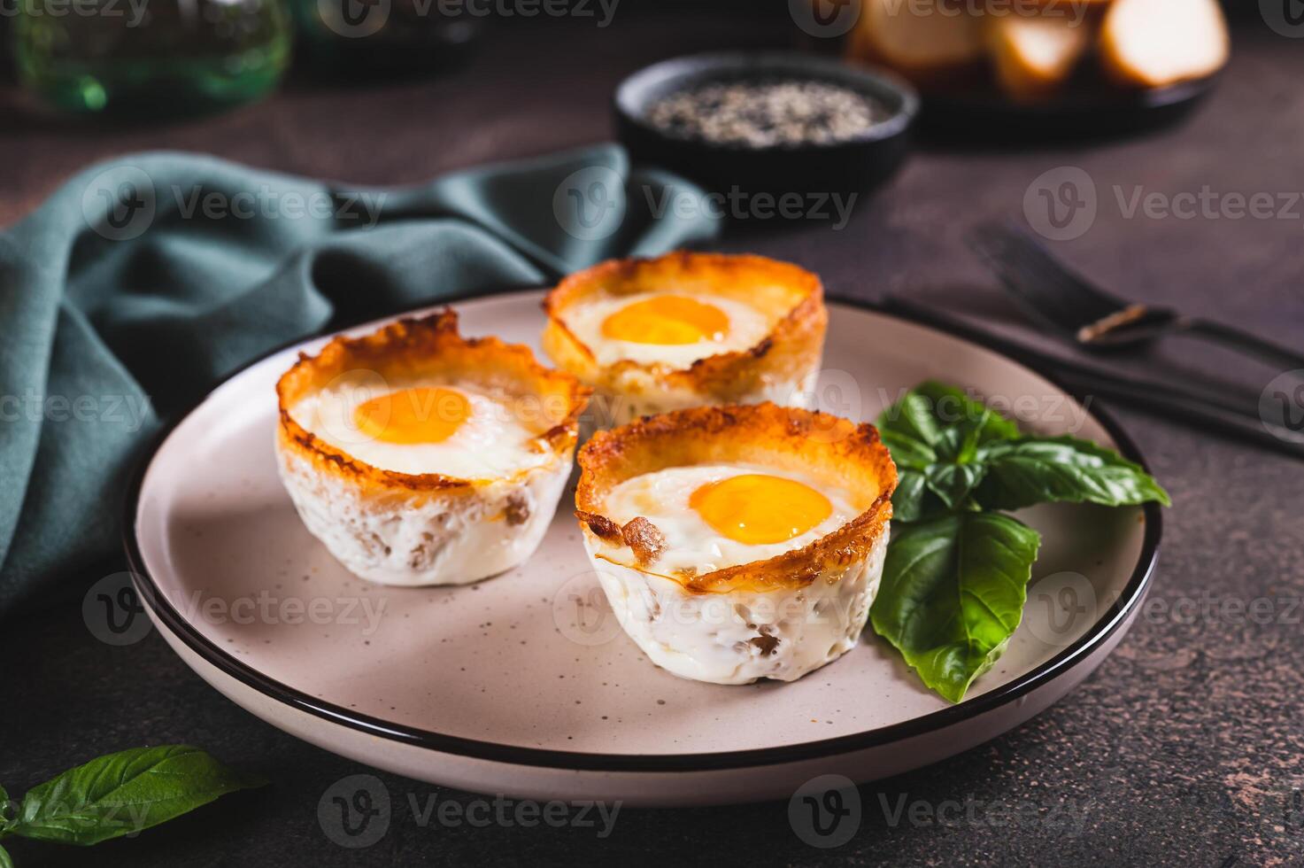 Chicken eggs baked in bacon and basil leaves on a plate on the table photo