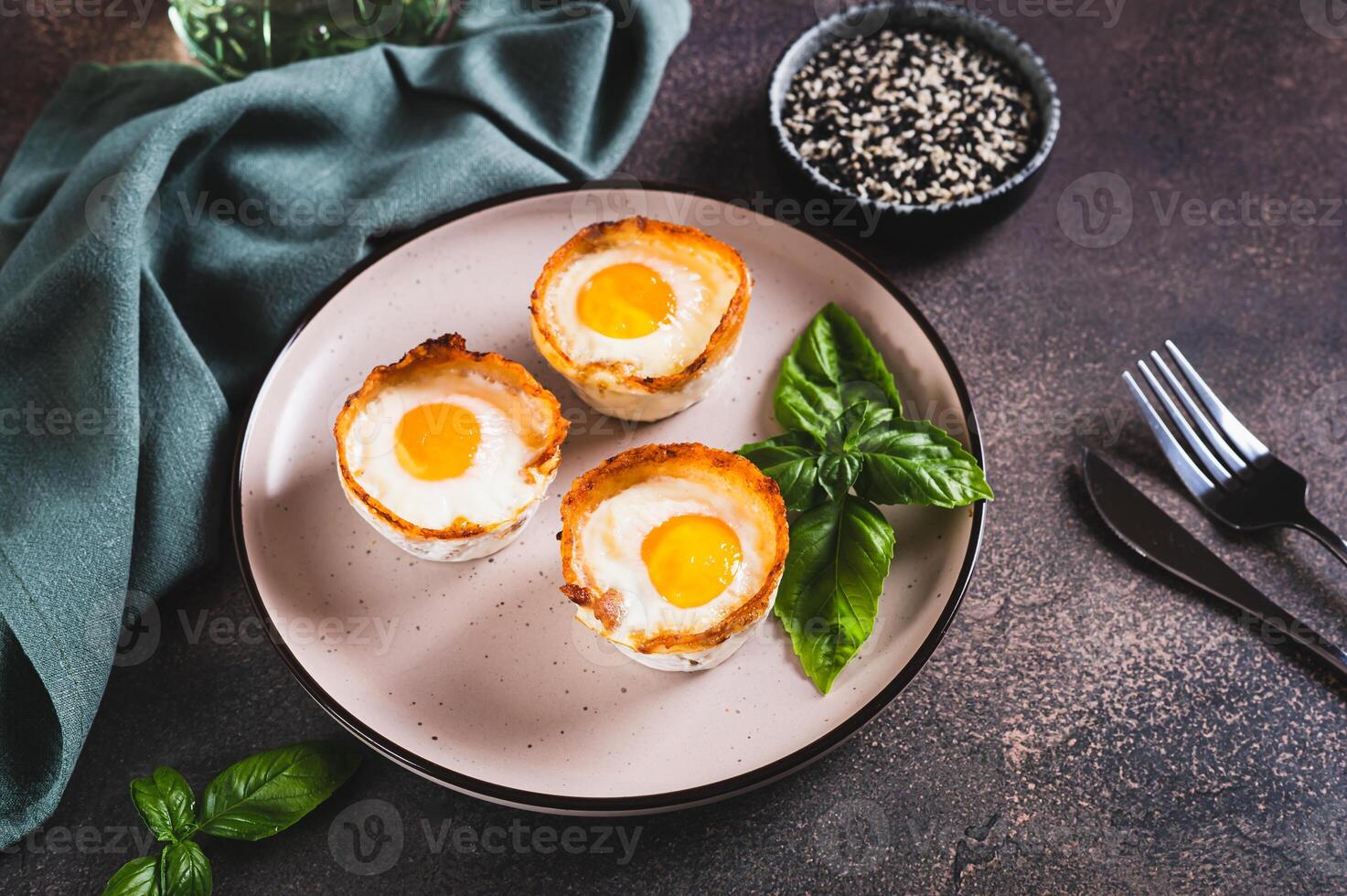 Baked egg and bacon rolls with basil on a plate on a table photo