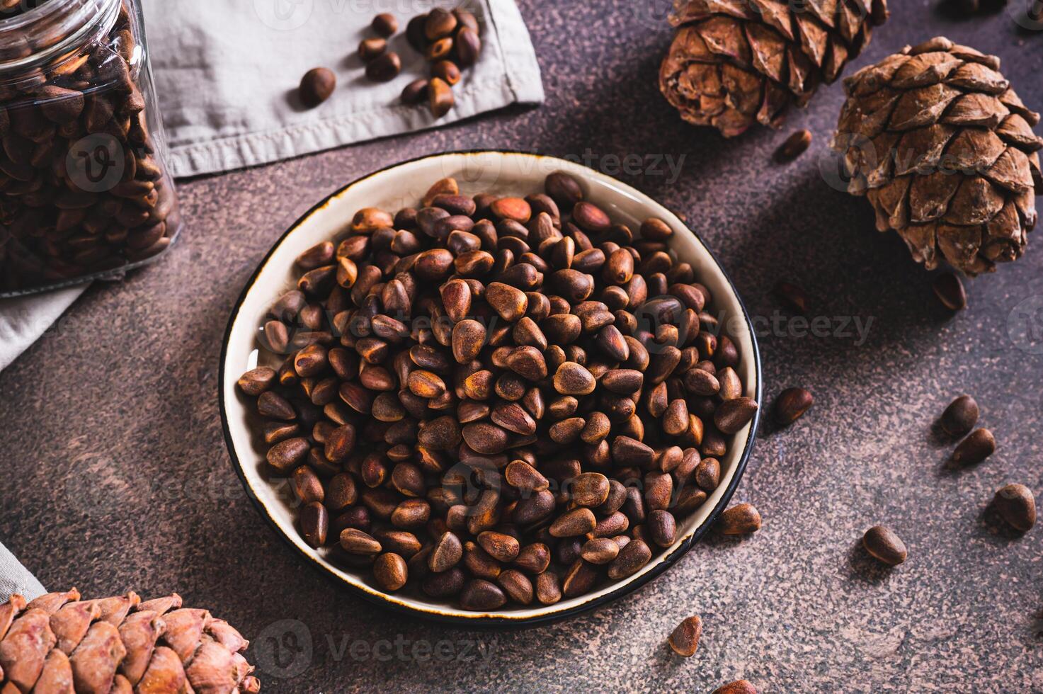 Unshelled pine nuts on a tray and pine cones on a table photo