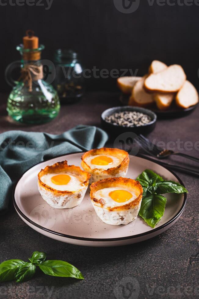 Chicken eggs baked in bacon and basil leaves on a plate on the table vertical view photo