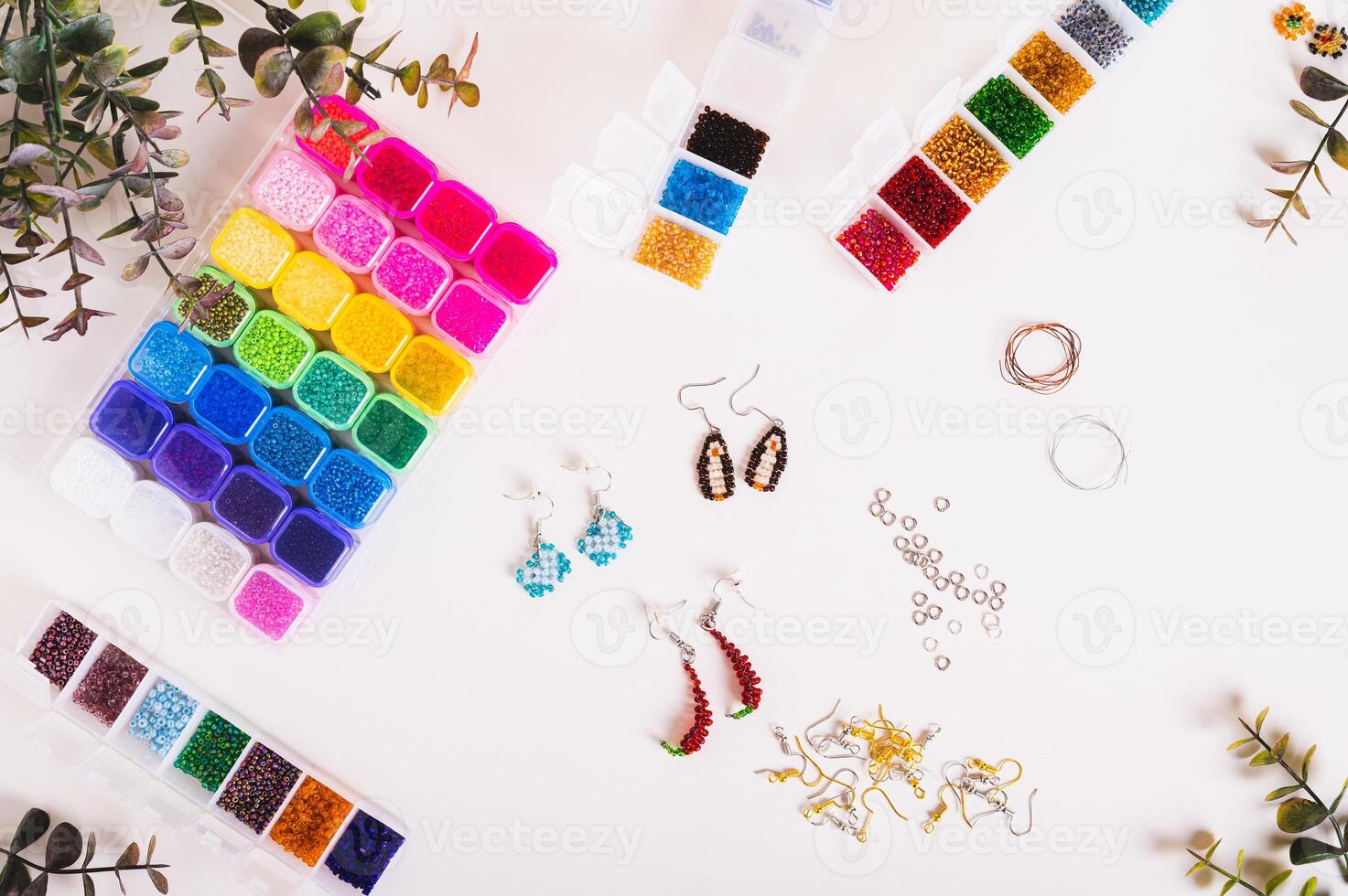 Beautiful beaded earrings, wire, fittings and boxes with colorful beads on the table top view photo