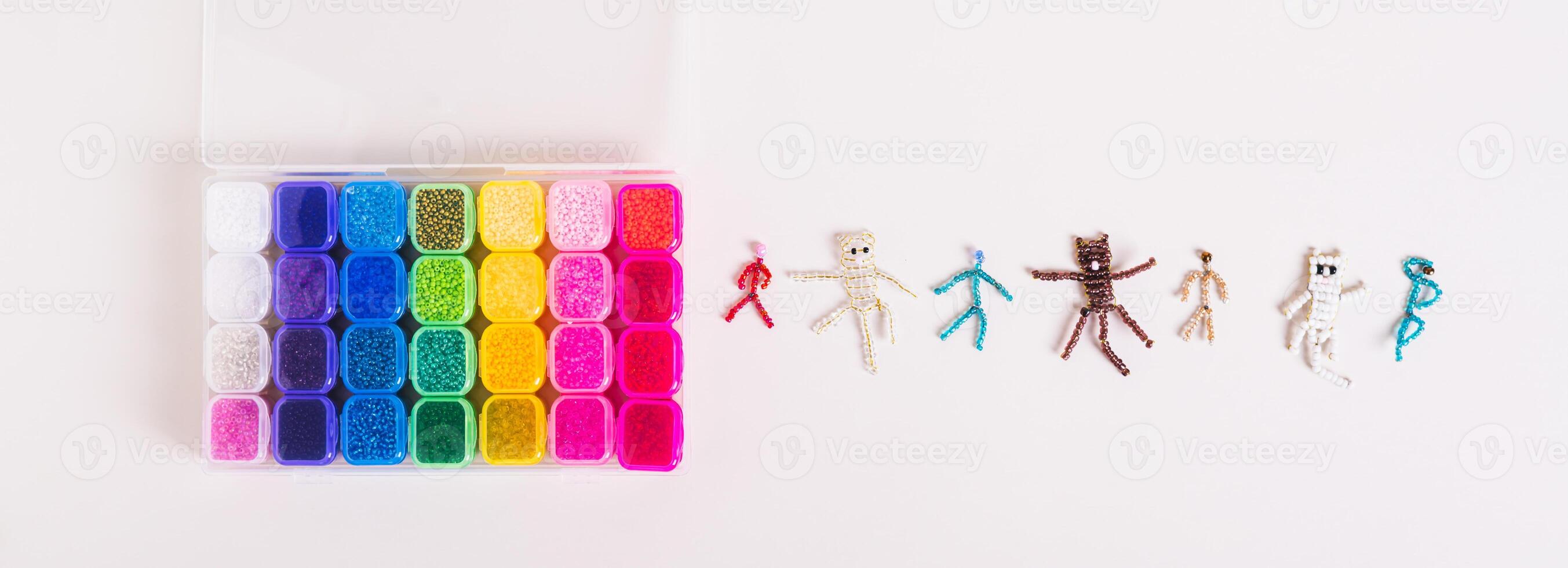Box with multi-colored beads and woven figures on the table top view web banner photo