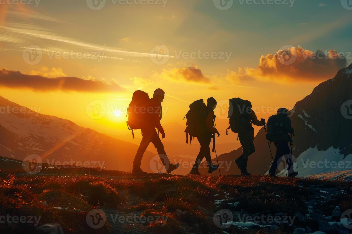 A group of tourists with backpacks walks through the mountains at sunset. The concept of travel, an active lifestyle. photo