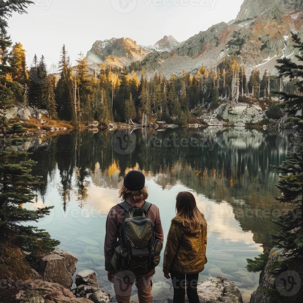 A couple of travelers are looking at a mountain lake. An overview of the trip. The concept of travel and active life. photo