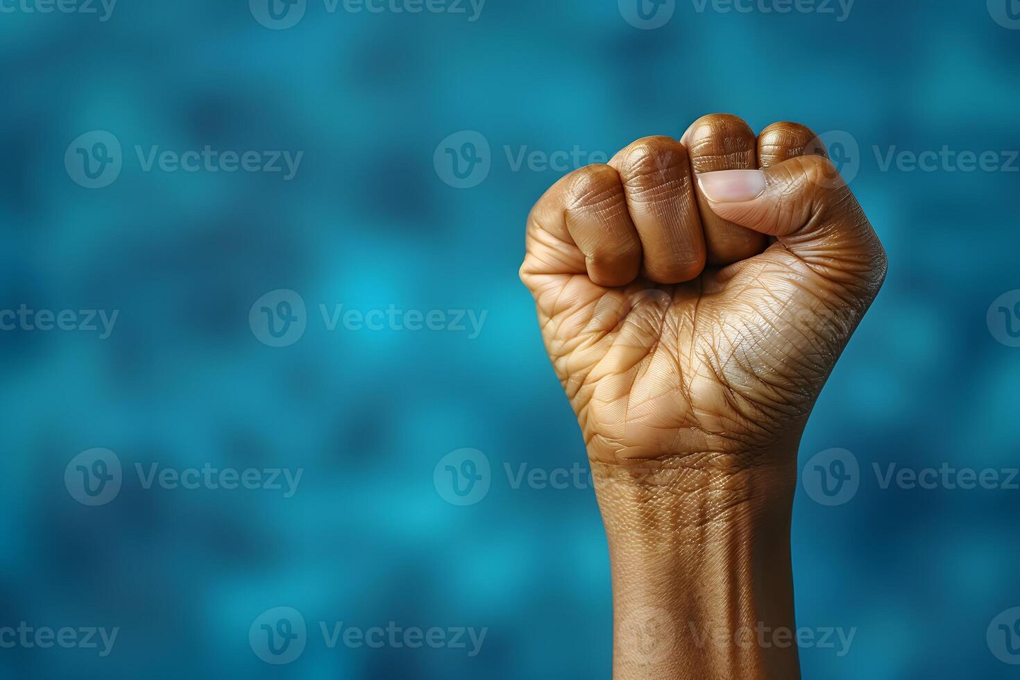 Power and Strength - Close-Up of a Raised Fist in Front of Blurred Blue Background - Symbol of Unity and Resilience photo