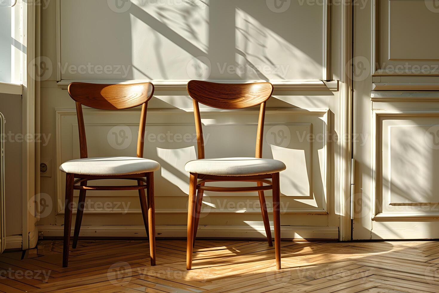 Pair of Mid-Century Modern Wooden Chairs Against Sunlit Paneled Wall photo