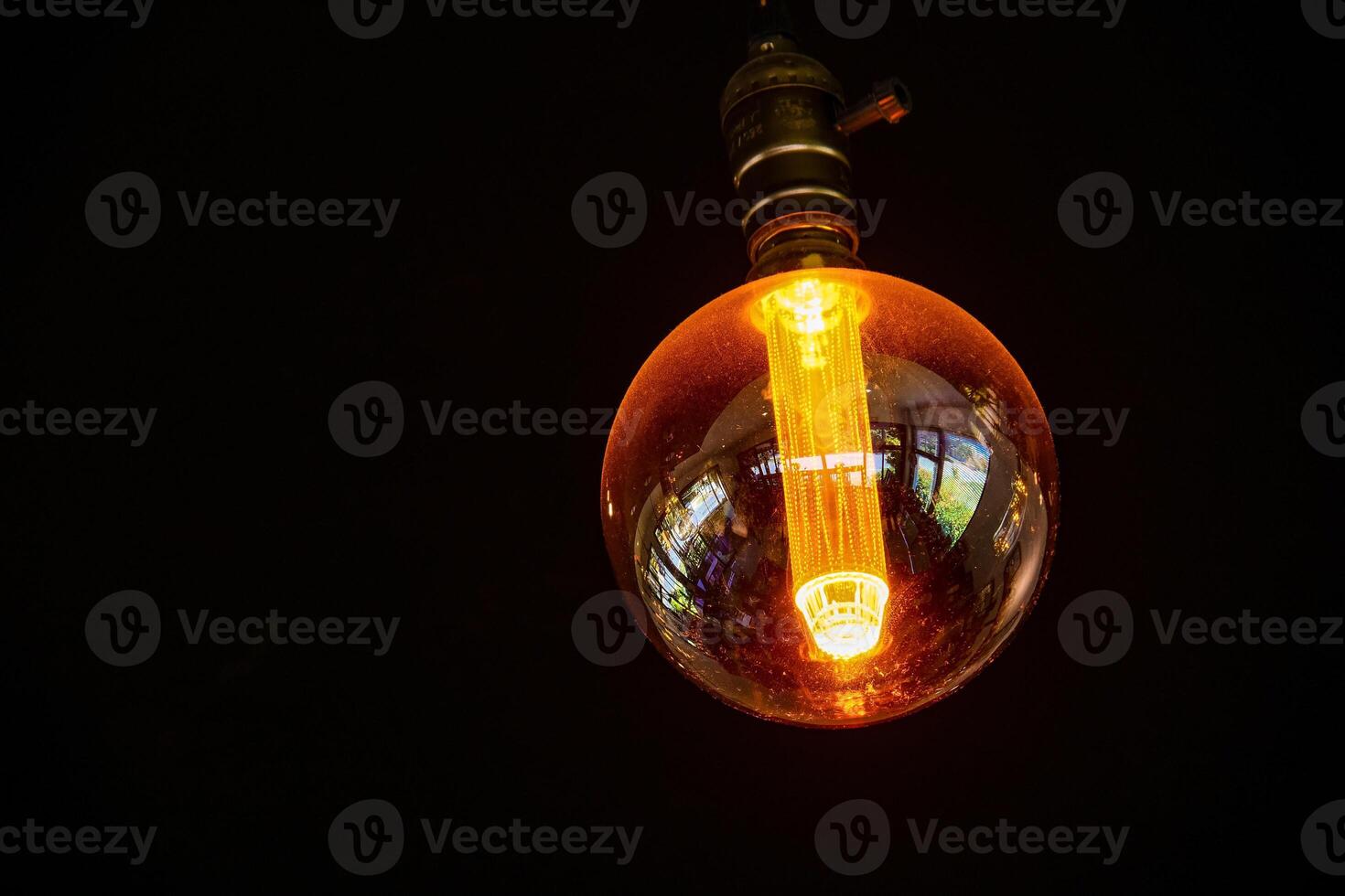Close-Up of a Vintage Edison Light Bulb Glowing in the Dark with Warm Orange Light photo