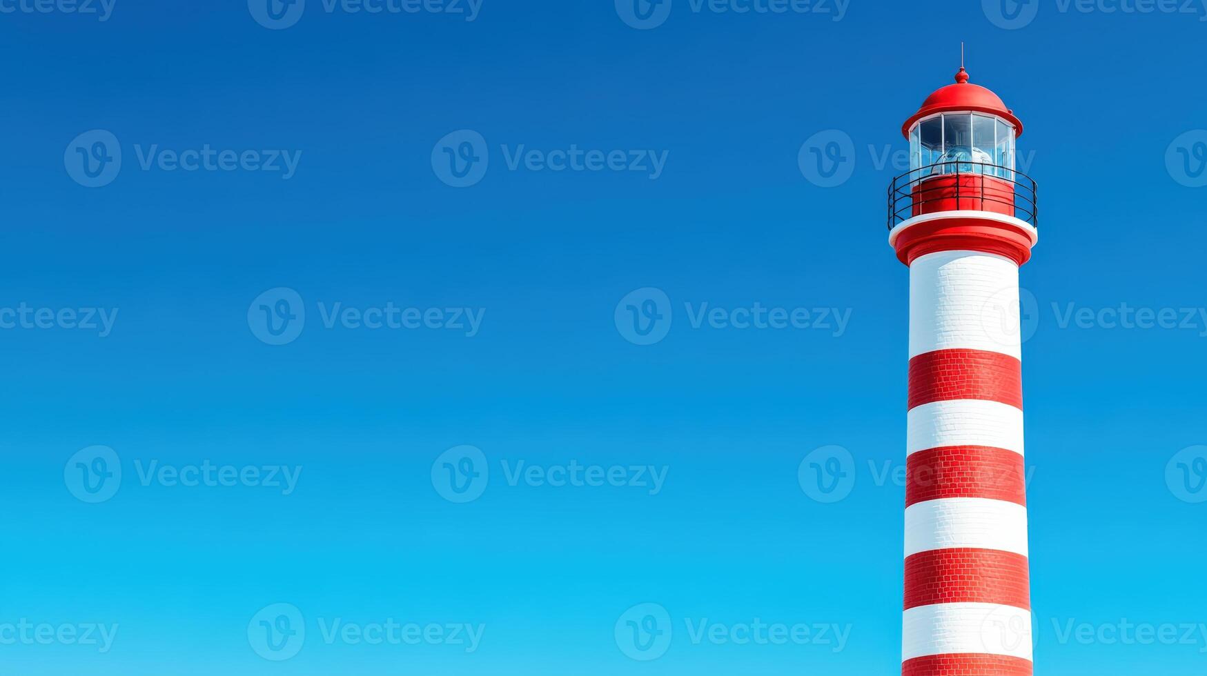 Red and white striped lighthouse against clear blue sky, symbolizing guidance and safety. Ideal for coastal, maritime, and navigational themes. photo