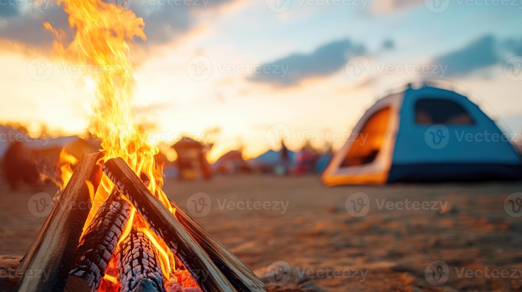 Cozy campfire with a tent in the background during a beautiful sunset, perfect for outdoor adventures and camping enthusiasts. photo