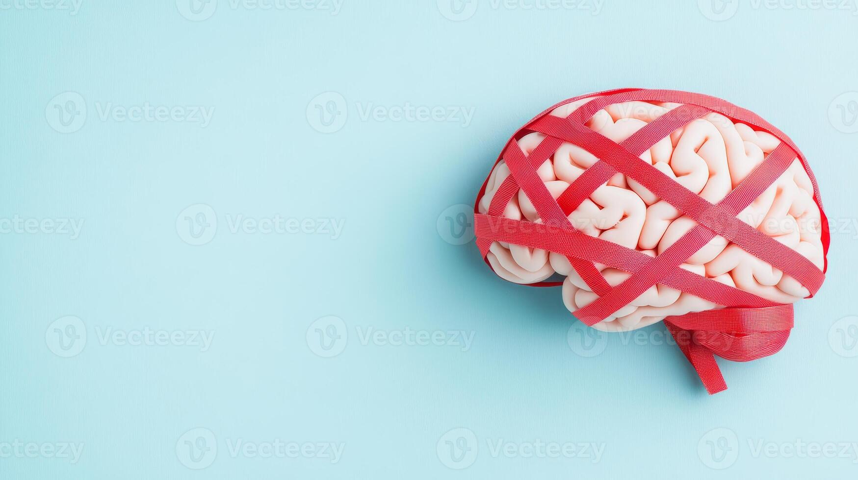 Human brain wrapped in red tape on pale blue background, symbolizing mental health and bureaucratic challenges. photo