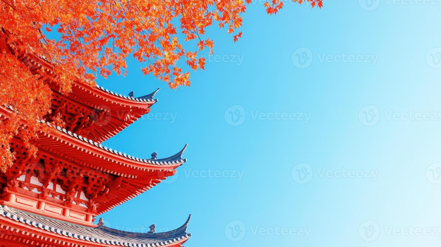 A vibrant autumn scene featuring a traditional pagoda surrounded by colorful red leaves against a clear blue sky. photo