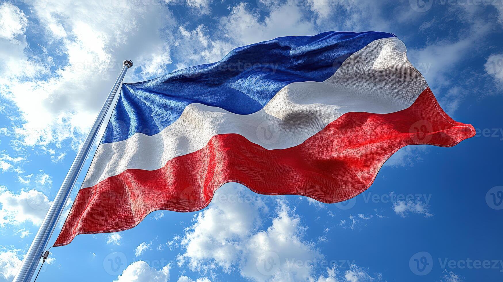 A vibrant flag waving in the wind against a backdrop of blue sky and clouds, symbolizing pride and identity. photo