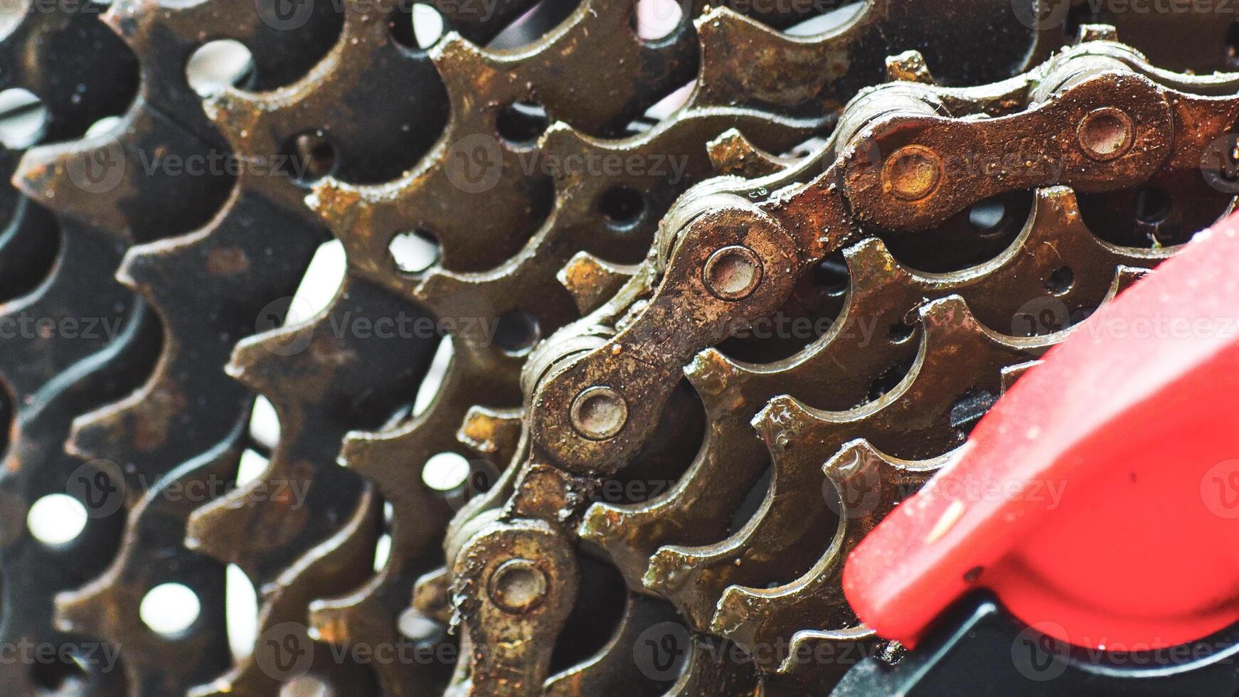 Close-up of a Bicycle Gear Mechanism with Rusty Chain and Red Derailleur photo