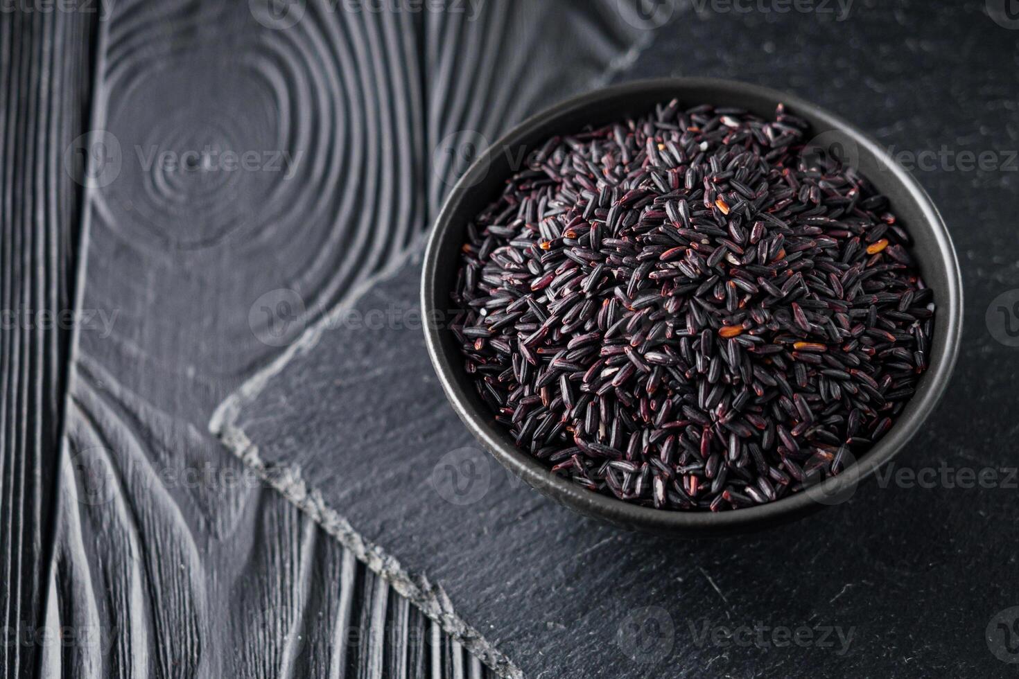 raw fresh black rice on black wooden rustic background photo