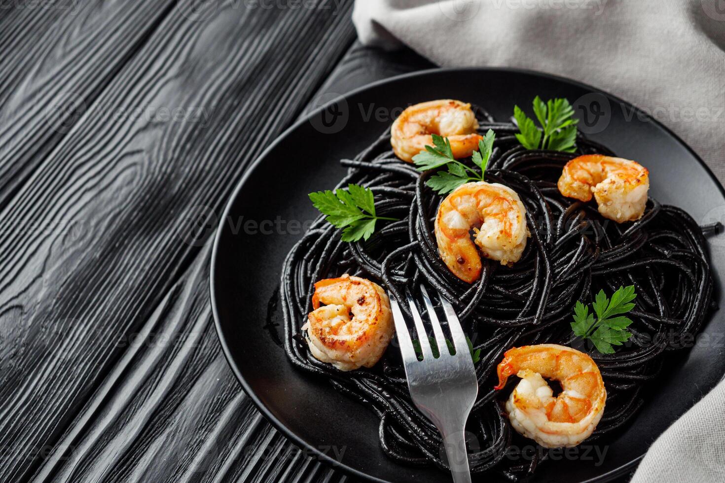 delicious black spaghetti pasta on a black rustic wooden background photo