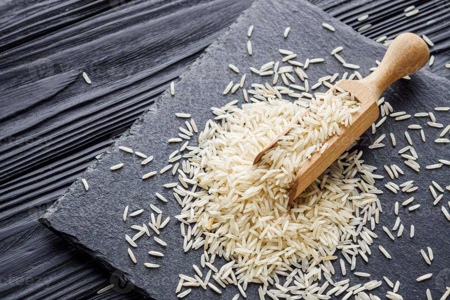 raw basmati rice on a black wooden background photo
